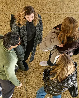 Four students stand together talking
