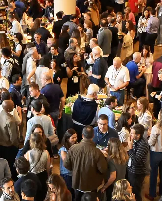 Large crowd gathers in a meeting space nearby banner that reads MIT Sloan Alumni Reunion