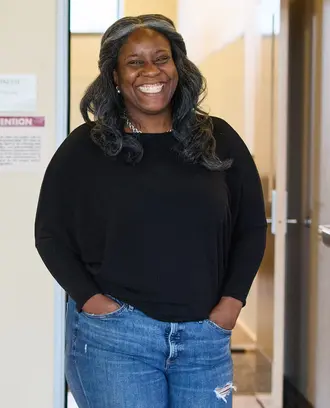 Alecia Asiamigbe walks through the halls of MIT Sloan, smiling at the camera