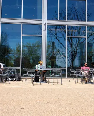 Students sitting at tables in front of the Memorial Drive entrance of E62