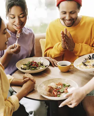 Waitress bringing food to a group of three friends in a restaurant.