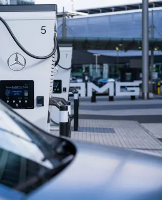 Contemporary electric vehicle charging station with Mercedes branding in a smart city setting.