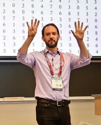 A man gestures while standing in front of a classroom