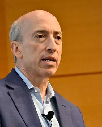 Man wearing business casual suit speaks before audience.