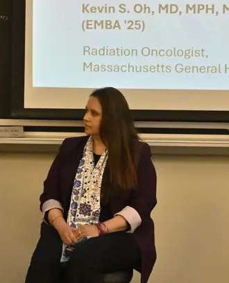 Three people on a panel listen to a fourth panel member speak.
