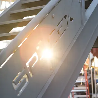 A railing with the sun shining through the SpaceX logo 