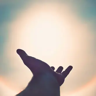 Silhouette of hand against a solar flare