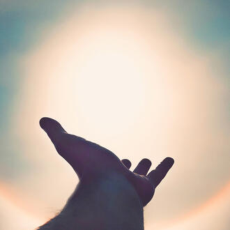 Silhouette of hand against a solar flare