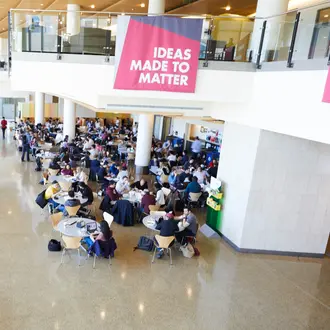 Lobby of MIT Sloan building with students sitting at tables