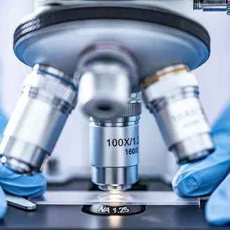 Glass slide being placed under a microscope.