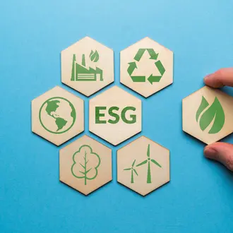 Hand pulling a hexagonal wooden tile away from a group of six other tiles with ESG in the middle