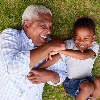 Grandfather and grandson play lying on grass, aerial view