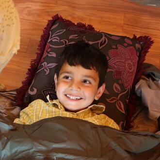 A young child gets comfortable in a TravlerPack sleeping bag.