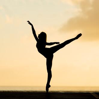Silhouette of ballerina dancing in the sunset