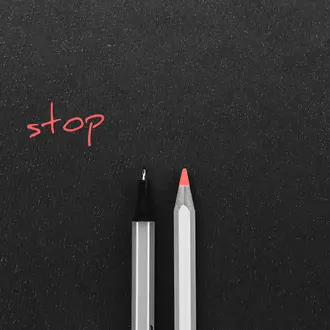 A pen and a colored pencil side by side with the word "stop" above
