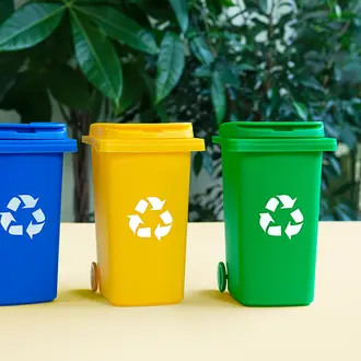 Three recycling bins in a row with leaves in the background