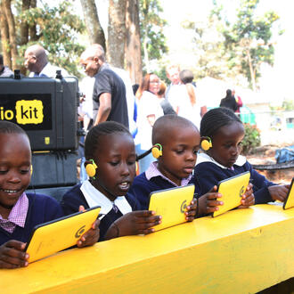 Children sitting in front of tablets smiling