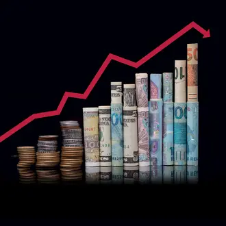 A red line graph over a stack of money in different currencies