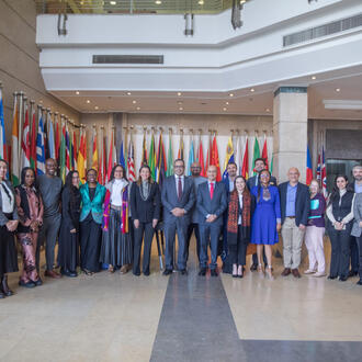 large group of entrepreneurs standing in official building in front of many flags