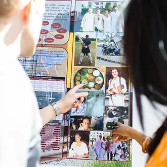 Backs of two people pointing at a poster 
