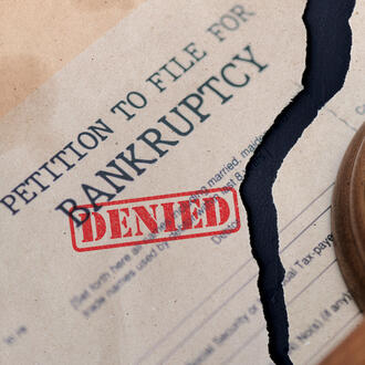 Petition to file for bankruptcy document torn in half with the stamp "denied" on it