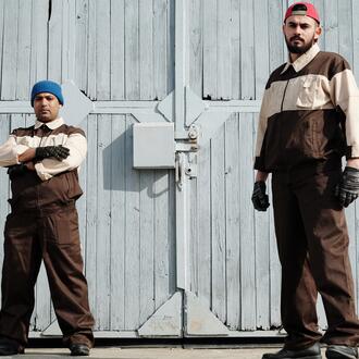 Image of two male workers standing in front of an industrial or warehouse-type building