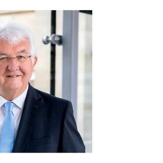 Robert Holzmann [older man with white hair, white skin and glasses wearing a dark suit with a light blue tie]