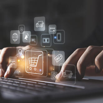 Young man using laptop with shopping cart icon