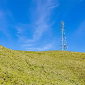 Image of an electrical tower on a hill with a blue sky background