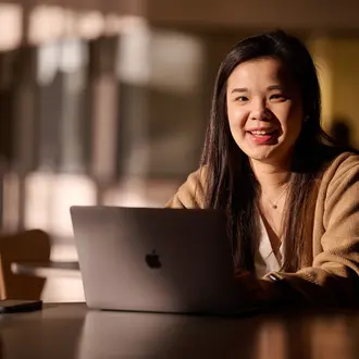 MBA Student Sharon Fan sits behind a laptop