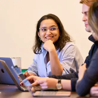 Kushi Pathak sits in front of a laptop, working with two other students