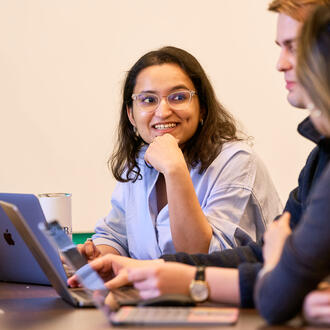 Kushi Pathak sits in front of a laptop, working with two other students
