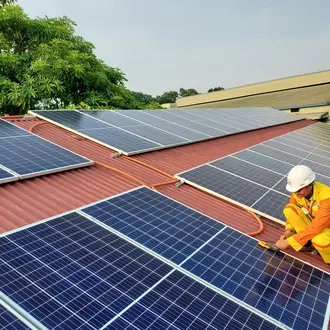 A construction worker installing solar panels on a rooftop