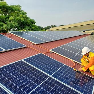 A construction worker installing solar panels on a rooftop