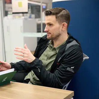 David Brown sits at a desk, talking to someone off camera. 