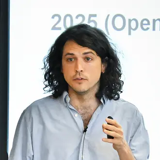 Mean holding remote speaks to audience in front of presentation