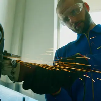 A worker in goggles is using a grinding machine