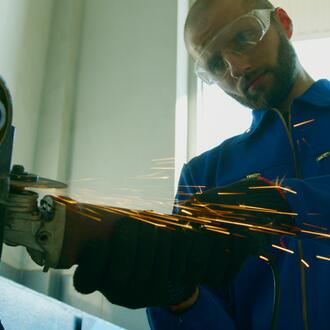 A worker in goggles is using a grinding machine