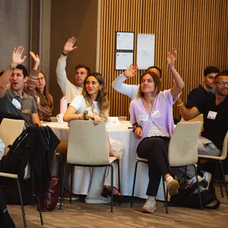 MIT MBA students raising their hands at an orientation program