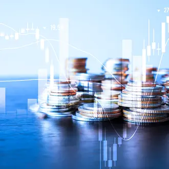 A stack of coins is overlayed with a stock ticker and bar charts