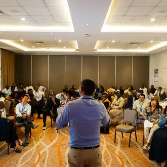 photograph of man speaking to a group of people