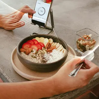 A person eats a healthy breakfast while looking at a phone app
