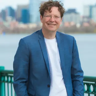 Headshot of a man outside in front of a river and skyline