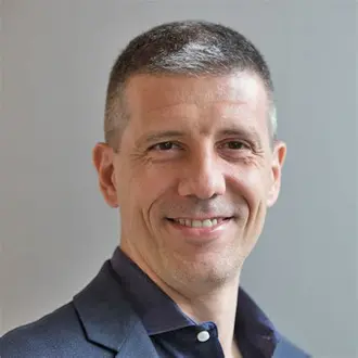 photo of a man with fair skin and gray hair wearing a navy blue shirt and jacket