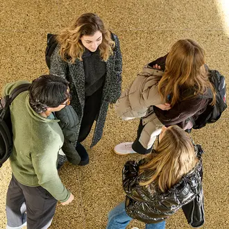 Four students stand together talking