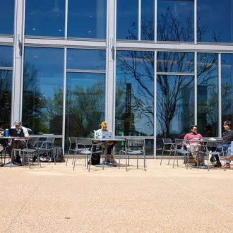 Students sitting at tables in front of the Memorial Drive entrance of E62