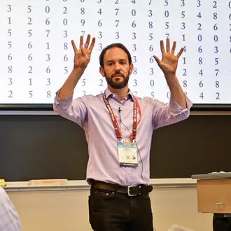 A man gestures while standing in front of a classroom
