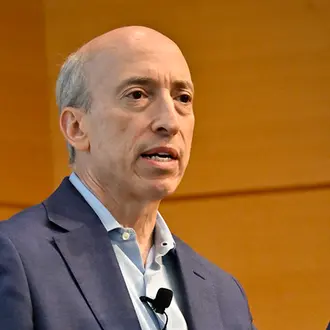 Man wearing business casual suit speaks before audience.