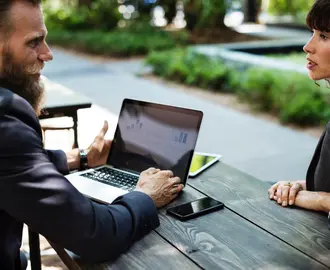 Man on laptop talking to woman