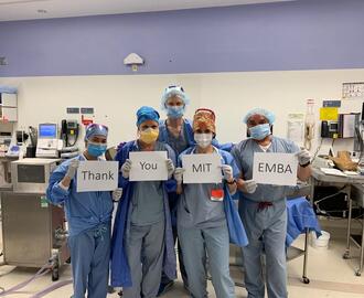 Hospital workers at BWH hold up signs reading "Thank you MIT EMBA"